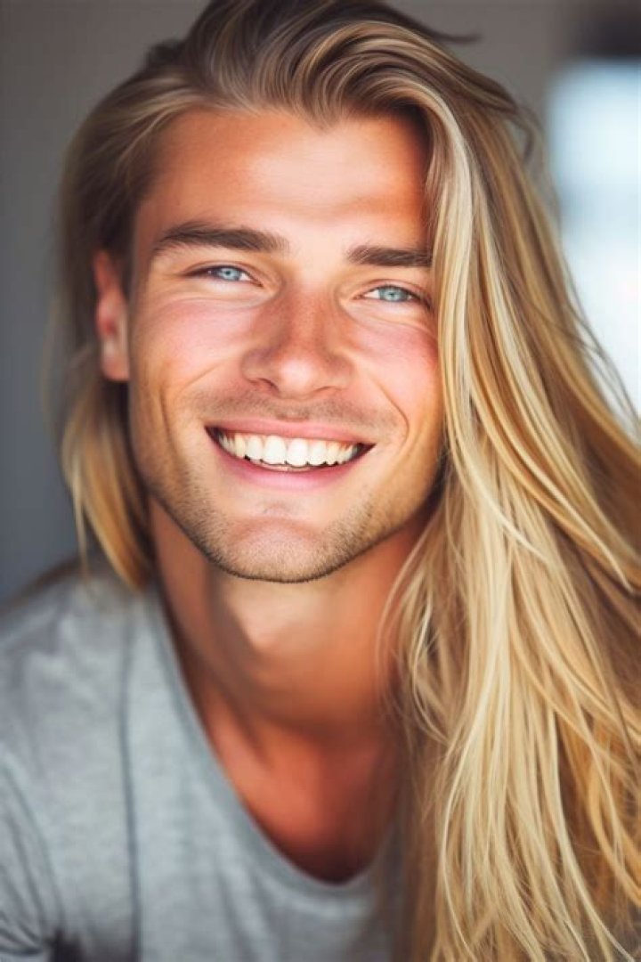 a man with long blonde hair wearing a white shirt